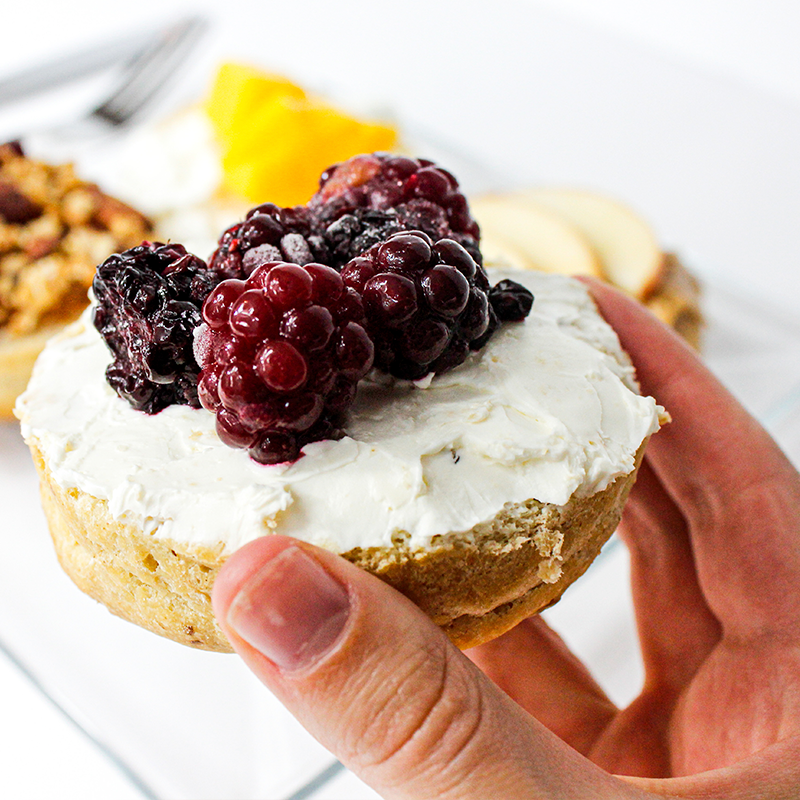 Mano que sostiene un bisquet de avena con moras y queso crema no tiene sellos por lo cual se considera saludable
