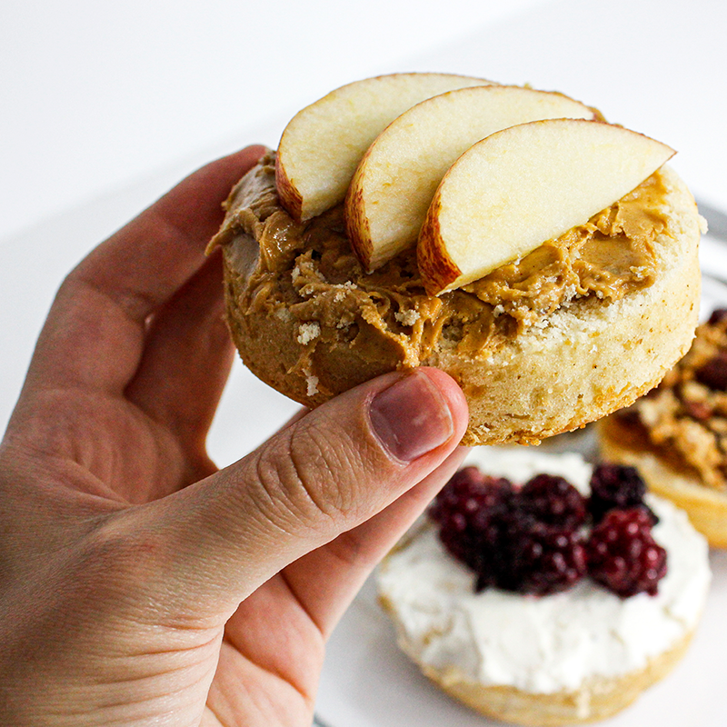 Mano que sostiene un bisquet vegano que tiene crema de maní y  manzana